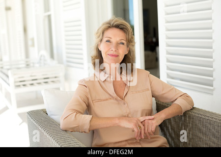 Ritratto di sorridere senior donna seduta sul patio Foto Stock