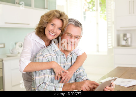 Ritratto di sorridente coppia senior con tavoletta digitale in cucina Foto Stock