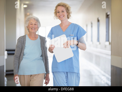 Ritratto di infermiera sorridente e senior paziente in ospedale corridoio Foto Stock