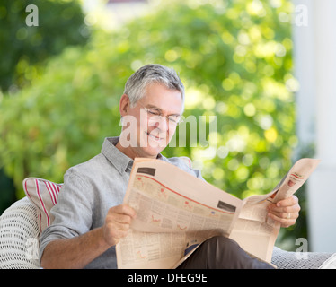 Senior uomo quotidiano di lettura sul patio Foto Stock