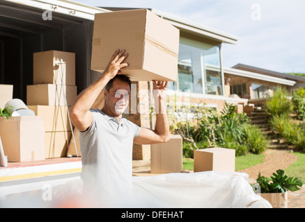 Uomo con scatola di cartone overhead vicino lo spostamento van nel viale di accesso Foto Stock