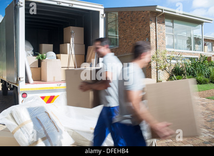 Movers trasportare le scatole di cartone nel viale di accesso Foto Stock