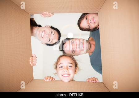 Famiglia guardando in giù a telecamera attraverso la scatola di cartone Foto Stock