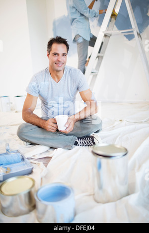 Ritratto di uomo sorridente di bere il caffè tra pittura forniture Foto Stock