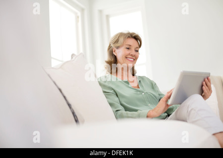 Donna senior con tavoletta digitale sul divano Foto Stock
