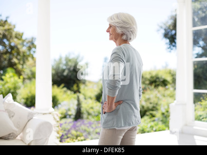 Senior donna in piedi sul patio Foto Stock