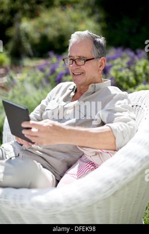 Senior uomo con tavoletta digitale in poltrona Foto Stock