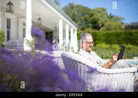 Senior uomo con tavoletta digitale in giardino Foto Stock