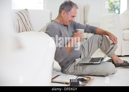 Senior uomo utilizzando laptop sul soggiorno piano Foto Stock