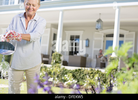 Donna senior di impianti di irrigazione in giardino Foto Stock