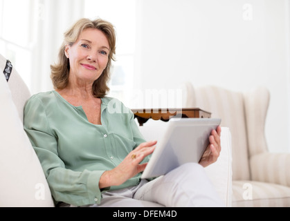 Ritratto di donna senior con tavoletta digitale sul divano Foto Stock