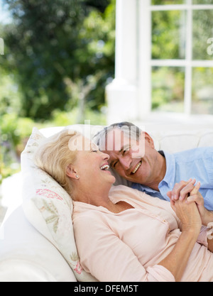 Coppia senior posa sul patio divano e tenendo le mani Foto Stock