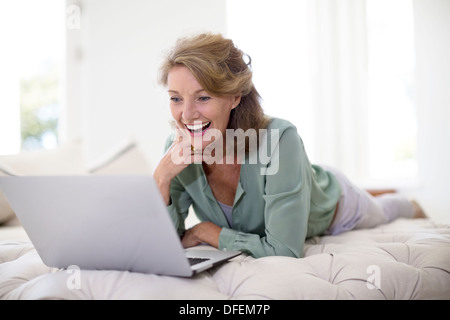 Senior donna utilizzando laptop in salotto Foto Stock