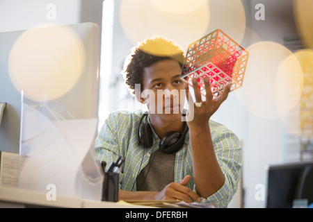 Imprenditore esaminando cube a scrivania in ufficio Foto Stock