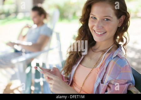 Donna che utilizza il telefono cellulare sul banco di lavoro Foto Stock