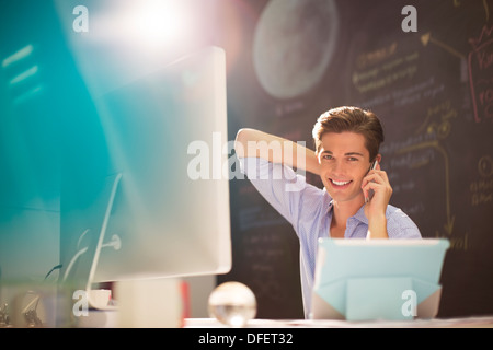 Imprenditore parlando al cellulare alla scrivania in ufficio Foto Stock