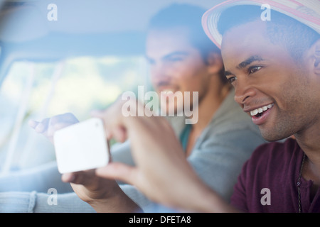 Gli uomini tramite telefono cellulare dotato di fotocamera digitale in auto Foto Stock