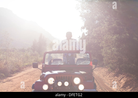 Uomo in piedi in sport utility vehicle su strada sterrata Foto Stock