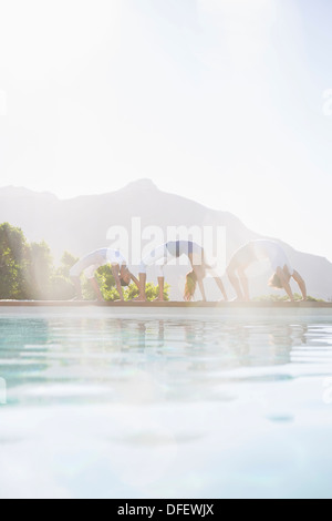 Persone che praticano lo Yoga a bordo piscina Foto Stock