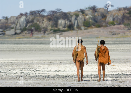 San bushman trackers attraversando a piedi il incrinato pan verso l'antico affioramento di granito di Kubu Island (Lekhubu), Makgadikgadi Pan, Botswana Foto Stock
