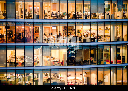 London, Regno Unito - Febbraio 2013: le persone a lavorare in un ufficio moderno edificio al crepuscolo. Foto Stock