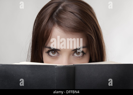 Solo gli occhi di donna di sbirciare da dietro un disco posteriore del libro Foto Stock