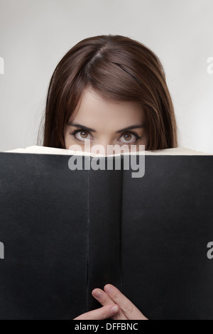 Solo gli occhi di donna di sbirciare da dietro un disco posteriore del libro Foto Stock