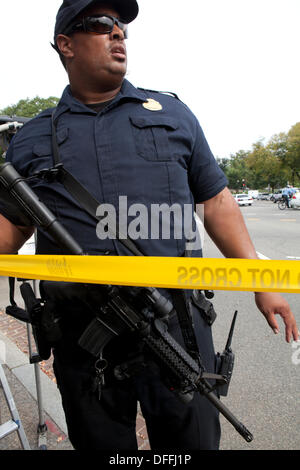 Poliziotto che trasportano un semi-auto fucile mettendo a linea di polizia il nastro a una scena del crimine - Washington DC, Stati Uniti d'America Foto Stock