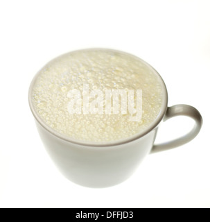 Un bianco tazza di latte con bolle isolato su uno sfondo bianco Foto Stock