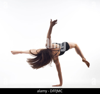 Ragazza ginnasta fare headstand su sfondo bianco Foto Stock