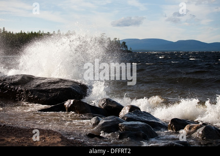 Big wave con schiuma bianca schizzi di pietra sulla riva del mare sullo sfondo Foto Stock