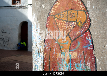 Graffiti raffiguranti un cattivo ragazzo. In background, un impiegato comunale incaricato della pulizia delle strade è a riposo ( Marocco) Foto Stock