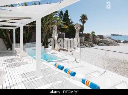 Sedie a sdraio e una piscina che si affaccia su Beach e Ocean Foto Stock