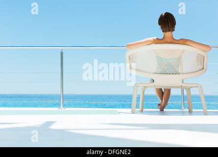 Donna in poltrona guardando vista oceano Foto Stock