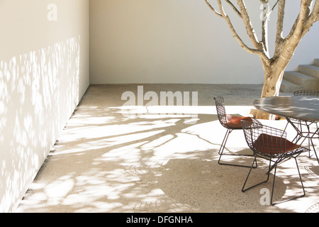 Tavolo e sedie gettando ombre in cortile Foto Stock