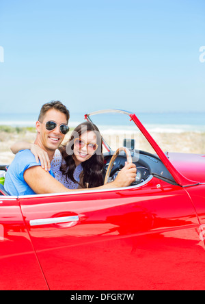 Giovane guida convertibili in spiaggia Foto Stock