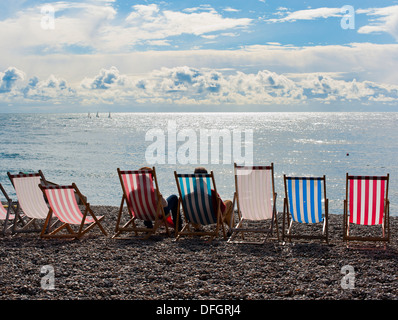 Due persone sedute a sdraio guardando il mare dalla spiaggia di birra Devon England Foto Stock