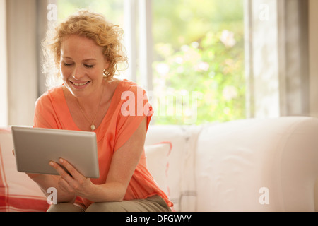 Donna con tavoletta digitale sul divano Foto Stock