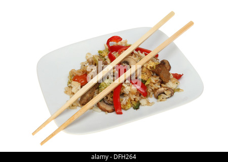 Carni bovine stir fry con bacchette su una piastra isolata contro bianco Foto Stock