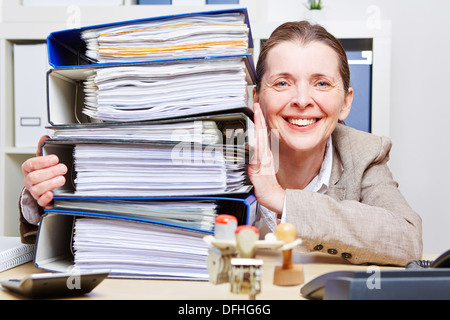 Happy business woman in ufficio con una pila di file Foto Stock