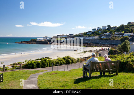 Giovane seduto su un banco da lavoro che si affaccia sul mare, Coverack, Cornwall Foto Stock