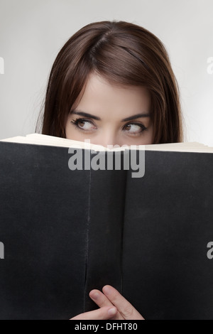 Solo gli occhi di donna di sbirciare da dietro un disco posteriore del libro Foto Stock