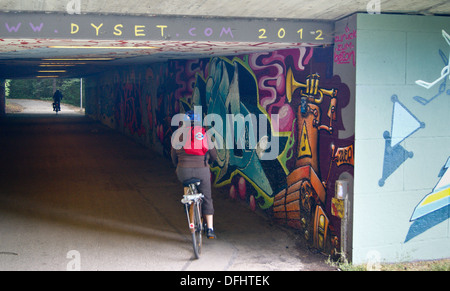 Un ciclista passa graffiti in un sottopassaggio pedonale, München (Monaco di Baviera), Bayern (Baviera), Germania Foto Stock
