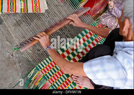 Anziani mano vietnamita rendendo reed colorati tappeti. Foto Stock