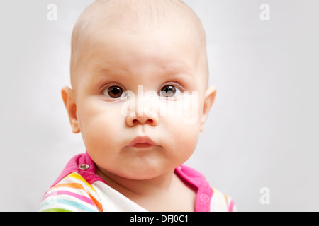 Poco calma brown eyed Caucasian baby closeup ritratto in studio su sfondo grigio Foto Stock