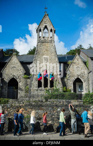 Bangor, Wales, Regno Unito. 5° ott, 2013.20 placcati luminosamente i giovani musicisti e creare colorati immagini statiche come essi si inseriscono i loro corpi in spazi e vuoti nella città di Bangor nel Galles del Nord. Ideato dal coreografo austriaco WILLI DORNER, "organismi in spazi urbani " è un viaggio nel mondo delle prestazioni, utilizzando ballerini locali e ginnasti. schiacciato ed equilibrato tra l'architettura della citta'. Centinaia di persone hanno seguito il loro corso attraverso la città su di un ora di tempo libero delle prestazioni. Credito: keith morris/Alamy Live News Foto Stock