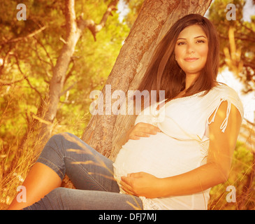 Donne incinte donna avendo divertimento all'aperto, relax nel bellissimo parco autunnale, cambiamenti meteorologici, giovane famiglia e vita nuova nozione Foto Stock