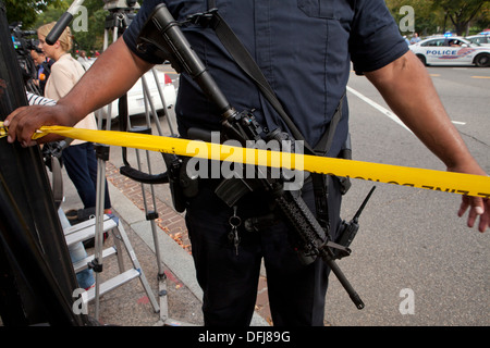 Poliziotto che trasportano un semi-auto fucile mettendo a linea di polizia il nastro a una scena del crimine - Washington DC, Stati Uniti d'America Foto Stock