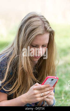 Giovane ragazza adolescente di età compresa tra i diciassette,sms sul cellulare /TELEFONO CELLULARE ALL'APERTO Foto Stock