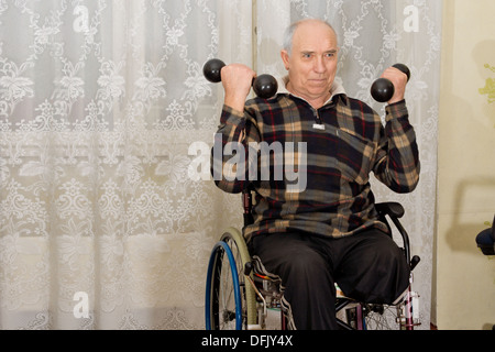 Portatori di handicap uomo senior con una minore amputazione della gamba che lavora fuori seduta nella sua sedia a rotelle utilizzando una coppia di manubri Foto Stock